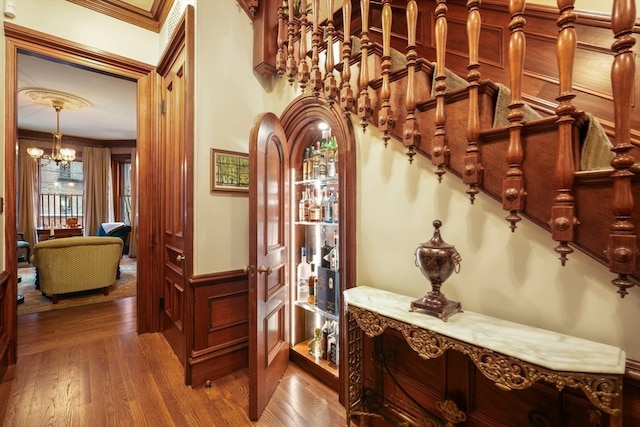 hallway featuring a notable chandelier, crown molding, and hardwood / wood-style floors