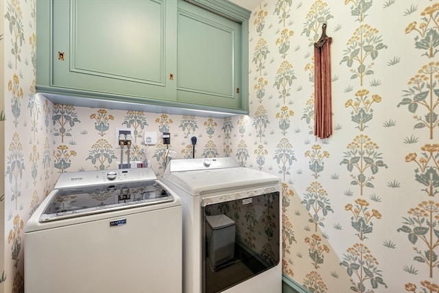 clothes washing area featuring independent washer and dryer and cabinets