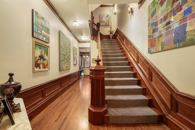 staircase with ornamental molding and hardwood / wood-style flooring