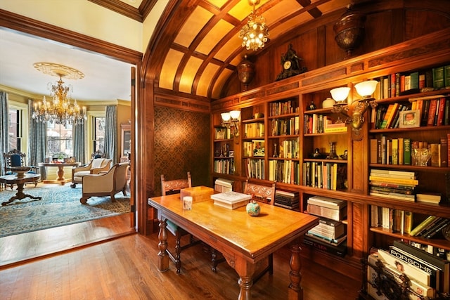 interior space featuring crown molding, vaulted ceiling, hardwood / wood-style floors, and a chandelier