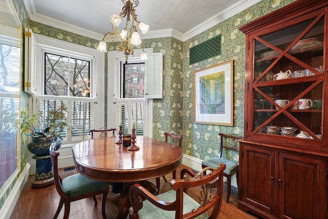 dining space with an inviting chandelier, crown molding, and hardwood / wood-style floors