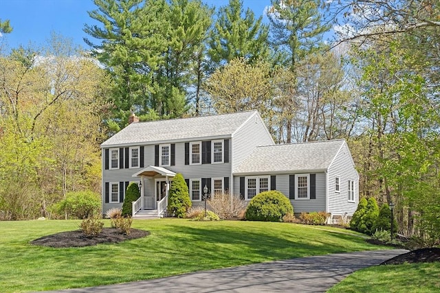 170 Olympic Ln, North Andover, MA 01845 - colonial-style house with a chimney, a front yard, and roof with shingles