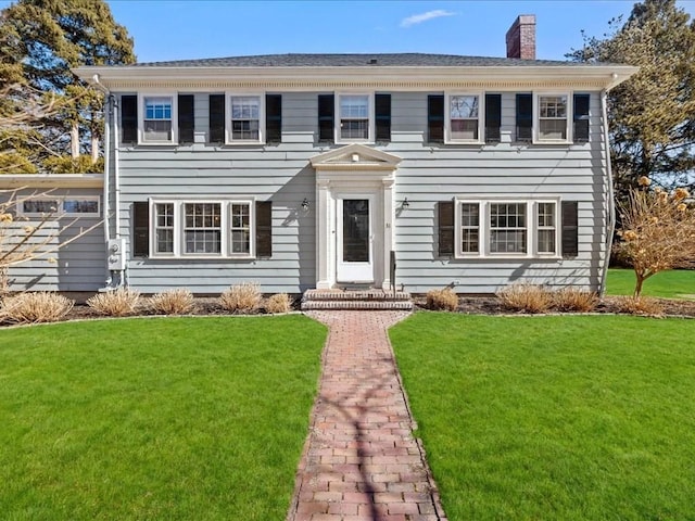 colonial house featuring a front lawn and a chimney