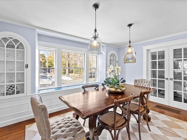 dining area with french doors, visible vents, crown molding, and wood finished floors