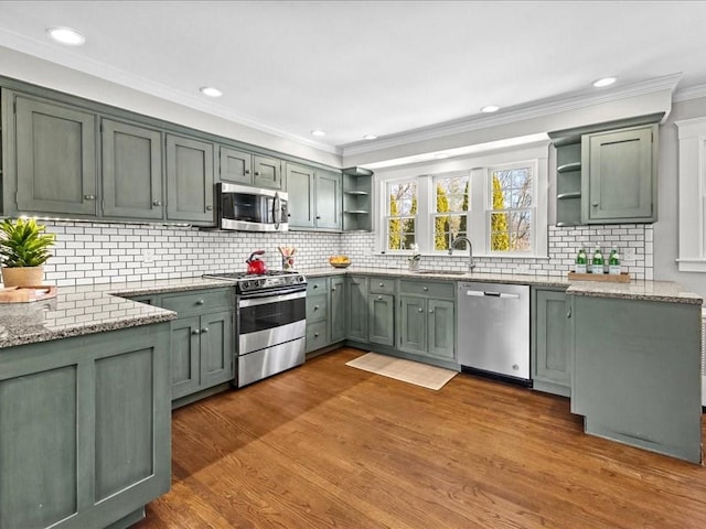 kitchen with stainless steel appliances, wood finished floors, light stone countertops, open shelves, and crown molding