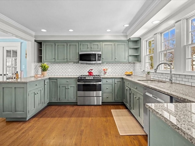 kitchen with open shelves, green cabinetry, a sink, and stainless steel appliances