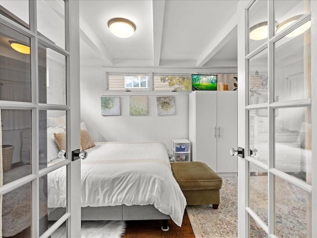 bedroom featuring french doors, beamed ceiling, and wood finished floors