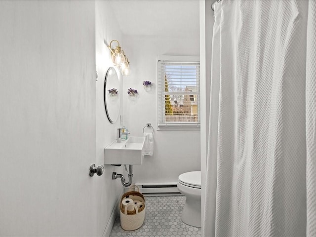 bathroom with toilet, a baseboard heating unit, a sink, baseboards, and tile patterned floors