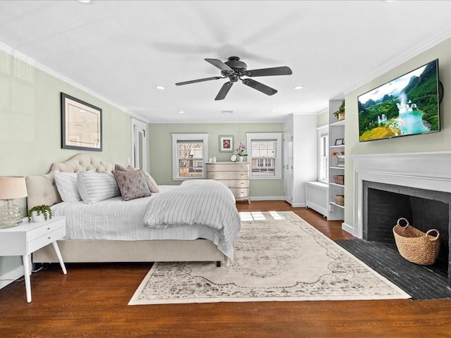 bedroom with a fireplace with flush hearth, ceiling fan, wood finished floors, and crown molding