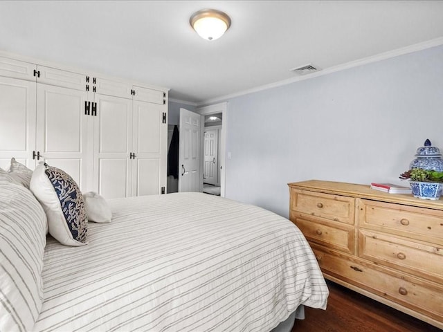 bedroom featuring dark wood-style floors, a closet, visible vents, and ornamental molding