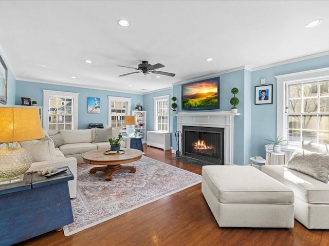 living area with a fireplace with flush hearth, ornamental molding, wood finished floors, and recessed lighting