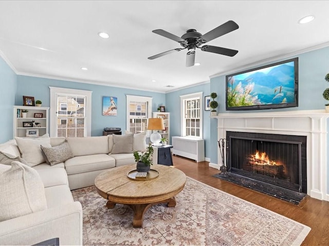 living area with recessed lighting, crown molding, wood finished floors, and a fireplace with flush hearth