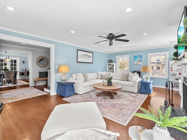 living area with a fireplace, ornamental molding, wood finished floors, and recessed lighting