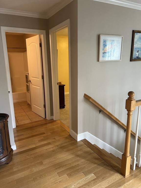 1 Hayloft Ln Unit 1, Marshfield, MA 02050 - hall with light wood-style floors, ornamental molding, and an upstairs landing