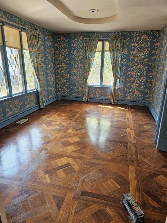 unfurnished room with wallpapered walls, a raised ceiling, and baseboards