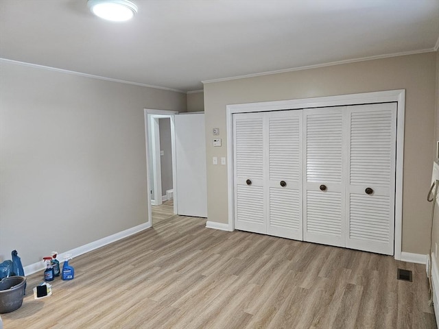 unfurnished bedroom with crown molding, wood finished floors, baseboards, and a closet