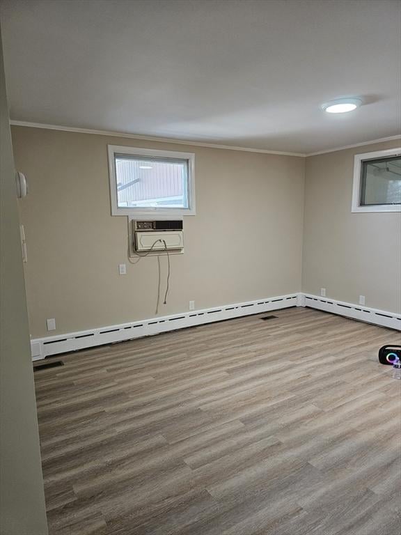 unfurnished room featuring a baseboard heating unit, wood finished floors, an AC wall unit, and ornamental molding