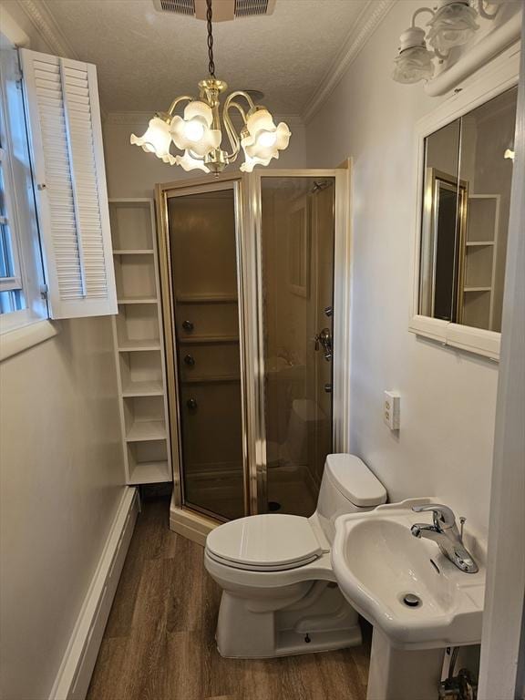 bathroom with crown molding, toilet, a stall shower, wood finished floors, and a sink