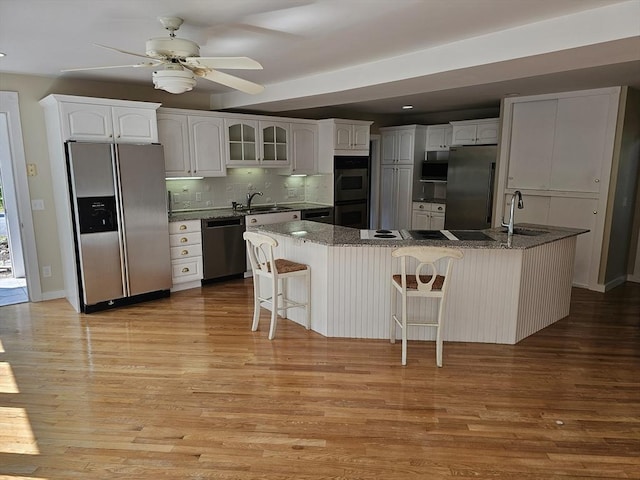 kitchen featuring light wood-style flooring, a sink, backsplash, stainless steel appliances, and white cabinets