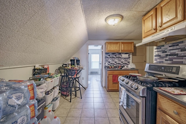 kitchen with stainless steel gas stove, light tile patterned flooring, a textured ceiling, and vaulted ceiling