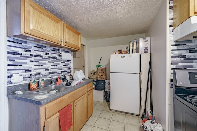 kitchen featuring light brown cabinets, tasteful backsplash, stainless steel range oven, white fridge, and light tile patterned floors