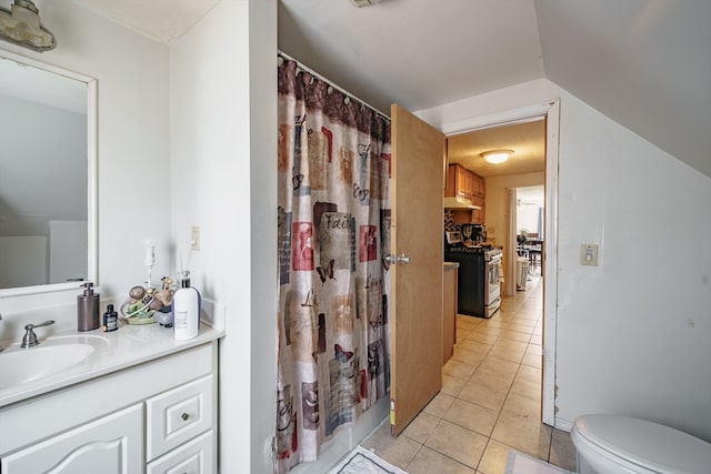 bathroom with tile patterned floors, vanity, lofted ceiling, and toilet