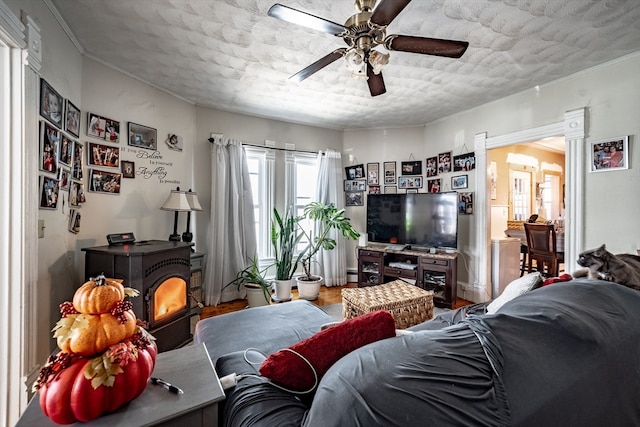 living room featuring ceiling fan, a wood stove, and a textured ceiling