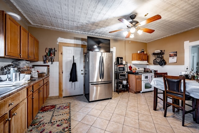 kitchen featuring stainless steel fridge, ceiling fan, light tile patterned floors, and white gas range oven