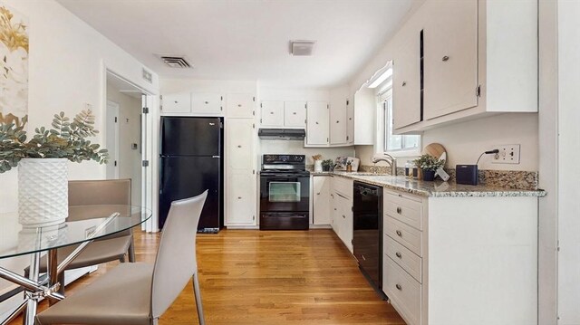 41 Lee Rd, Needham, MA 02494 - kitchen with black appliances, under cabinet range hood, a sink, light wood finished floors, and white cabinets