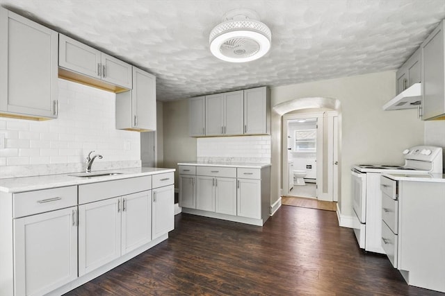 27 Whittier St, Fall River, MA 02724 - kitchen with white electric range oven, under cabinet range hood, arched walkways, decorative backsplash, and dark wood-style flooring