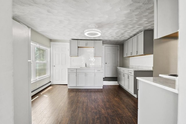 27 Whittier St, Fall River, MA 02724 - kitchen with a baseboard radiator, dark wood-type flooring, a textured ceiling, tasteful backsplash, and light countertops