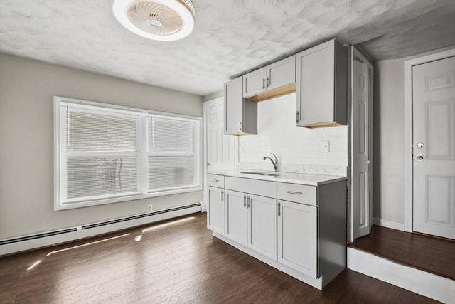 27 Whittier St, Fall River, MA 02724 - kitchen featuring baseboard heating, light countertops, a textured ceiling, decorative backsplash, and dark wood-style floors