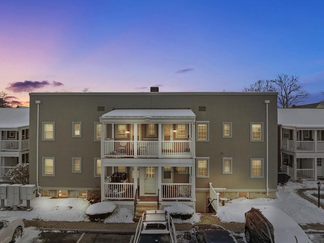 snow covered back of property featuring covered porch