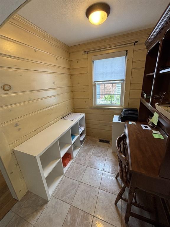 259 Gillette Ave, Springfield, MA 01118 - laundry room featuring a textured ceiling, light tile patterned floors, wood walls, an office area, and arched walkways