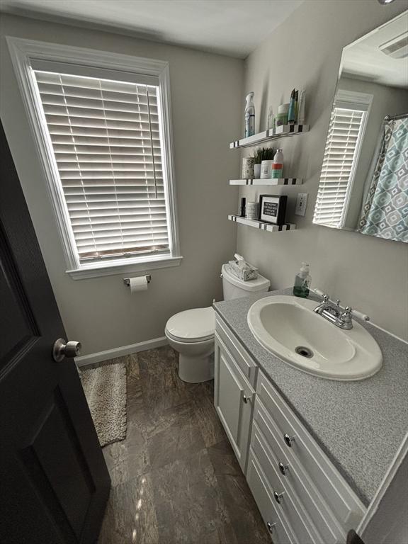 259 Gillette Ave, Springfield, MA 01118 - full bathroom with vanity, toilet, stone finish flooring, and baseboards