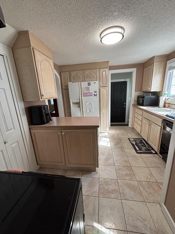259 Gillette Ave, Springfield, MA 01118 - kitchen featuring light brown cabinetry, white fridge with ice dispenser, a peninsula, a sink, and a textured ceiling
