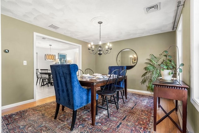 dining space with visible vents, baseboards, and wood finished floors