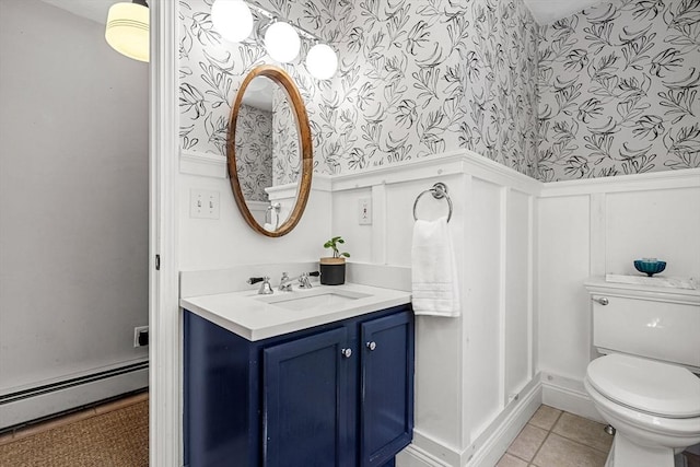 half bath with tile patterned flooring, wainscoting, toilet, wallpapered walls, and a baseboard heating unit