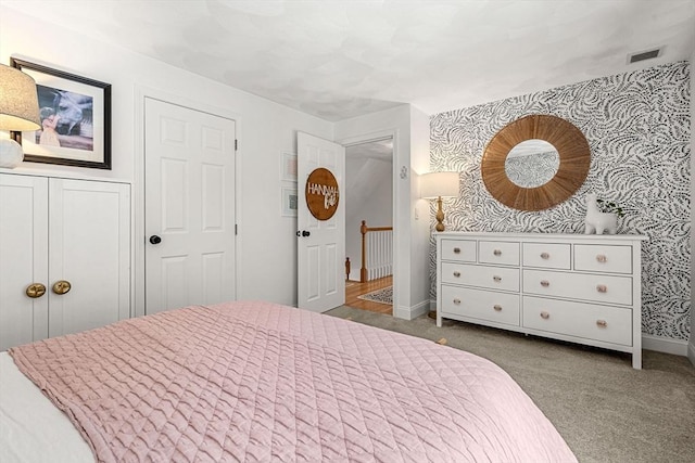 carpeted bedroom with wallpapered walls, visible vents, and baseboards