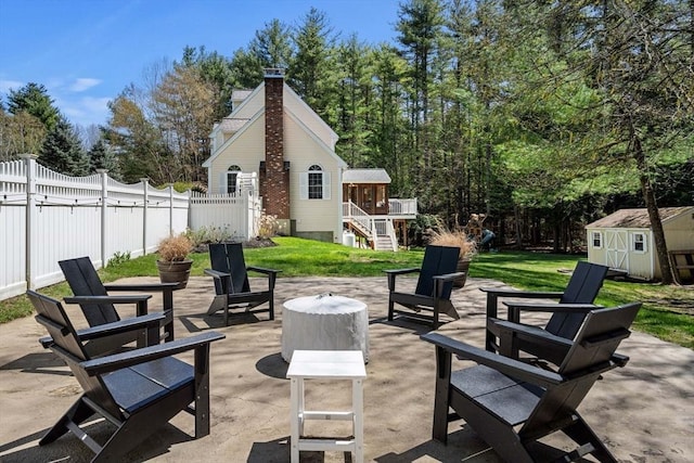 view of patio with fence, a shed, stairway, an outdoor structure, and a fire pit
