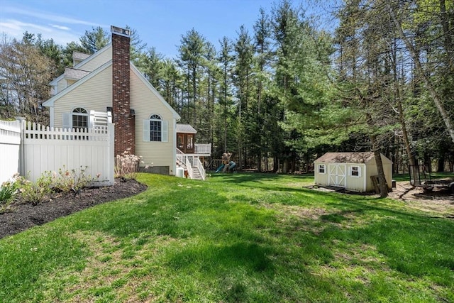 view of yard featuring an outbuilding, a playground, fence, and a storage shed