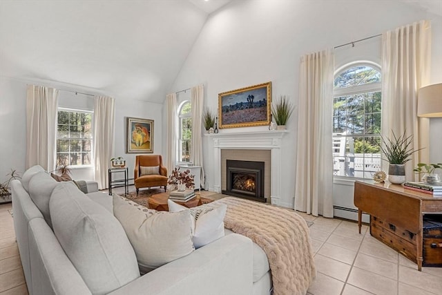 living area with a fireplace with flush hearth, a baseboard heating unit, a healthy amount of sunlight, and high vaulted ceiling