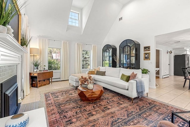 living area featuring a brick fireplace, a healthy amount of sunlight, light tile patterned floors, and a towering ceiling