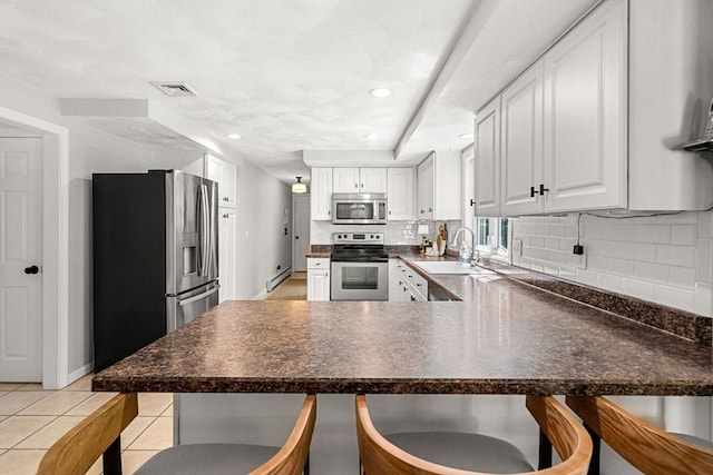 kitchen with stainless steel appliances, a peninsula, decorative backsplash, a baseboard radiator, and visible vents