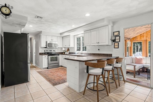 kitchen with light tile patterned floors, appliances with stainless steel finishes, a peninsula, and visible vents