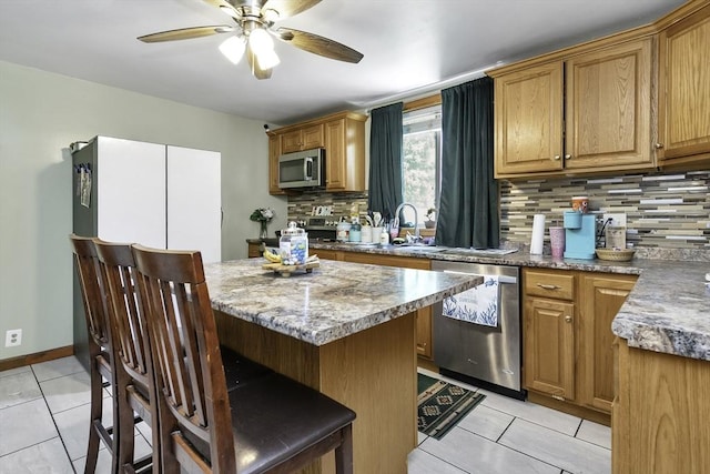kitchen with ceiling fan, stainless steel appliances, backsplash, and light tile patterned flooring