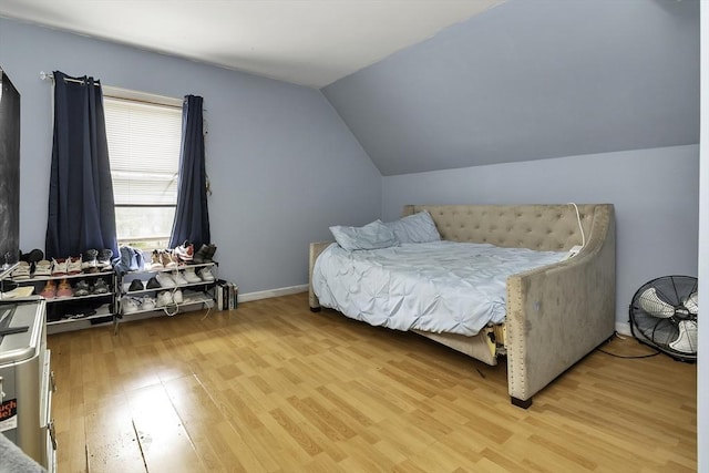 bedroom with lofted ceiling, baseboards, and light wood-type flooring