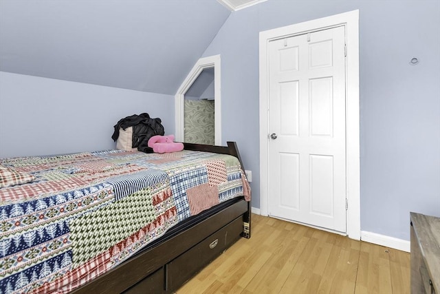 bedroom with light wood finished floors, baseboards, and lofted ceiling