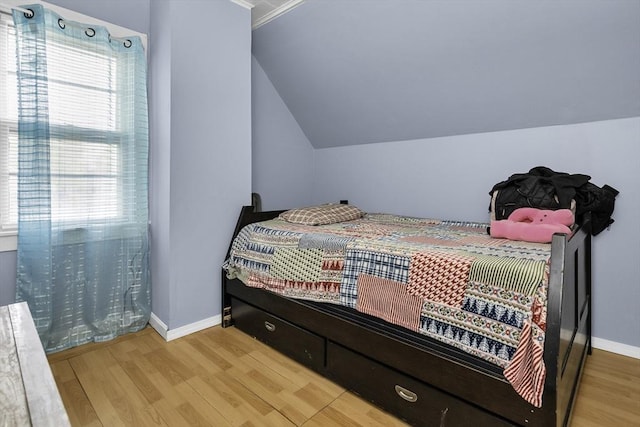 bedroom with vaulted ceiling, wood finished floors, and baseboards