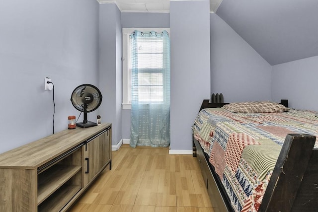 bedroom with baseboards, light wood-type flooring, and vaulted ceiling